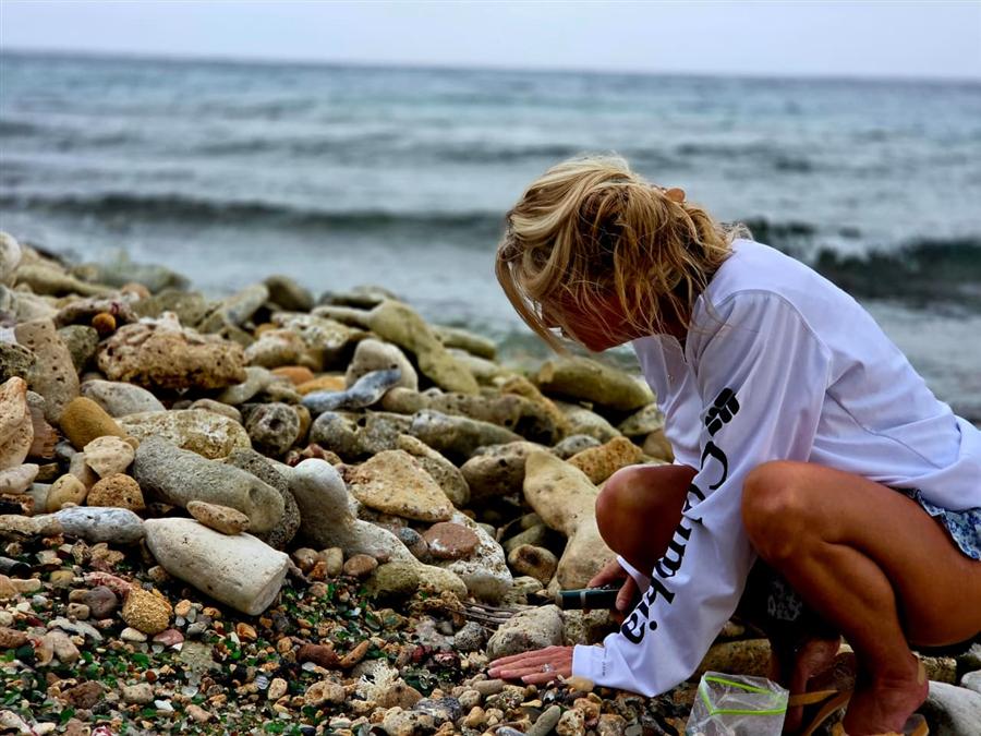 Guest crouching on the shore of Sea Glass Island hunting for sea glass